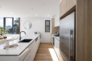 A modern kitchen with a central island, stainless steel appliances, and a view through the window. - Waterfront 2B 2Bath Pk,GYM,Pool&BBQ (Surfers Paradise)