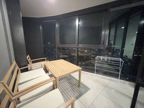 A balcony with a table and chairs, a metal drying rack, and a city view at night. - New L63 Hill River CBD View&Pool & Sauna (Surfers Paradise)