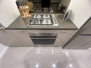 A kitchen with a gas stove, a built-in oven, and a coffee maker. - New L63 Hill River CBD View&Pool & Sauna (Surfers Paradise)