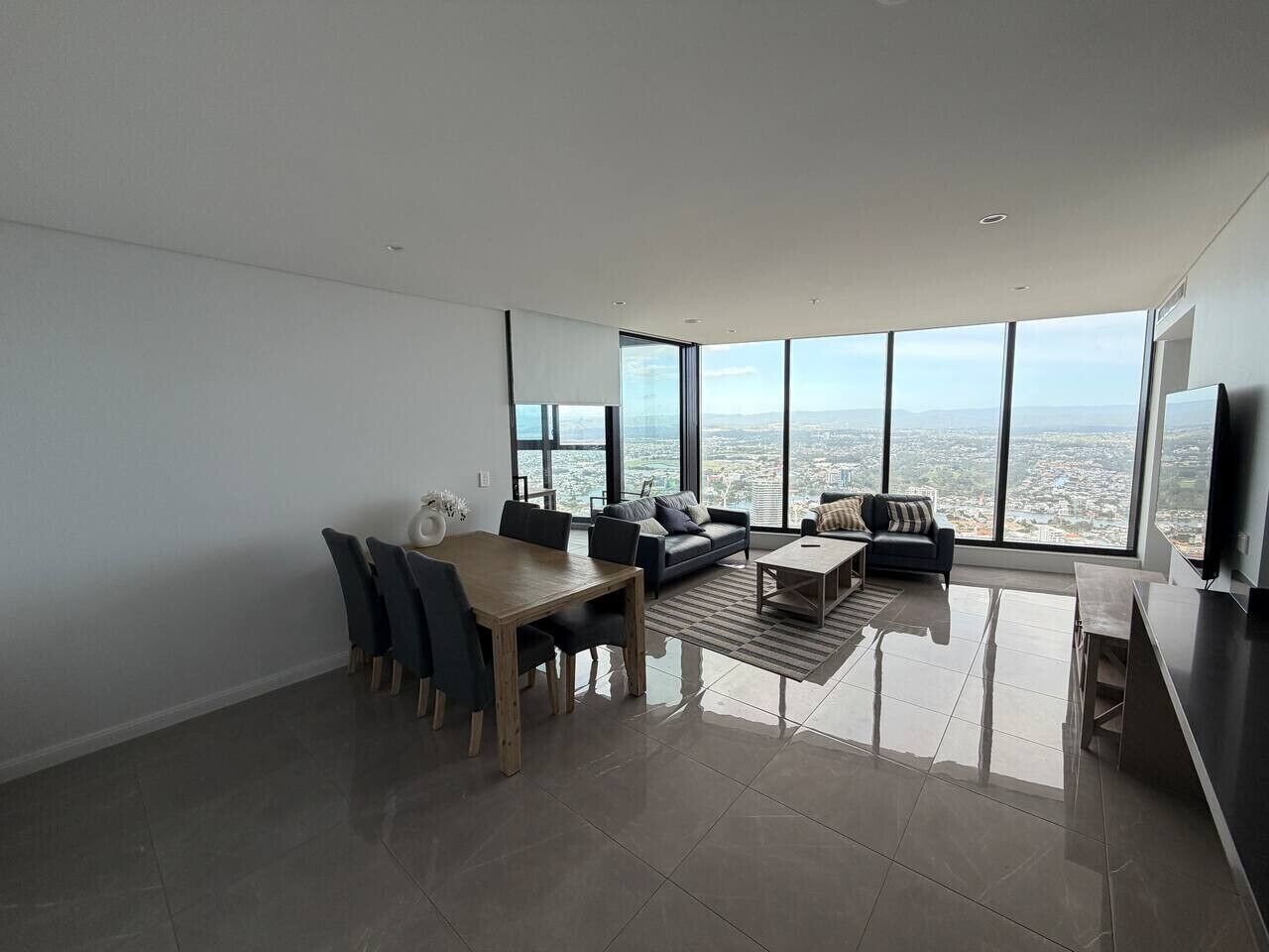 Una sala de estar moderna con comedor, ventanas amplias y vista a la ciudad.