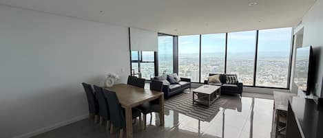 Una sala de estar moderna con comedor, ventanas amplias y vista a la ciudad.