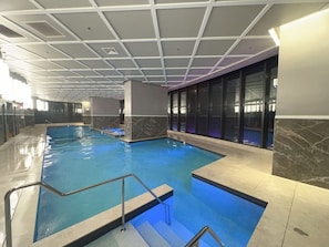 An indoor swimming pool with a tiled floor and a ceiling with a grid pattern. - New L63 Hill River CBD View&Pool & Sauna (Surfers Paradise)