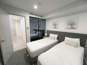 A hotel room with two beds, a wardrobe, a bedside table, and a mirror. - New L63 Hill River CBD View&Pool & Sauna (Surfers Paradise)