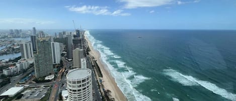 Un paisaje urbano costero con rascacielos, una playa y cielo despejado.