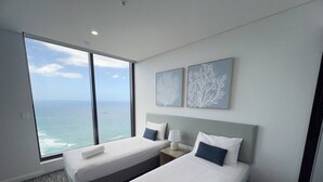 A hotel room with two beds, a large window with a view of the ocean, and two wall-mounted artwork pieces. - Meriton L47 with SeaViews and CarPark (Surfers Paradise)