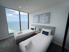 A hotel room with two beds, a large window with a view of the ocean, and two wall-mounted artwork pieces. - Meriton L47 with SeaViews and CarPark (Surfers Paradise)