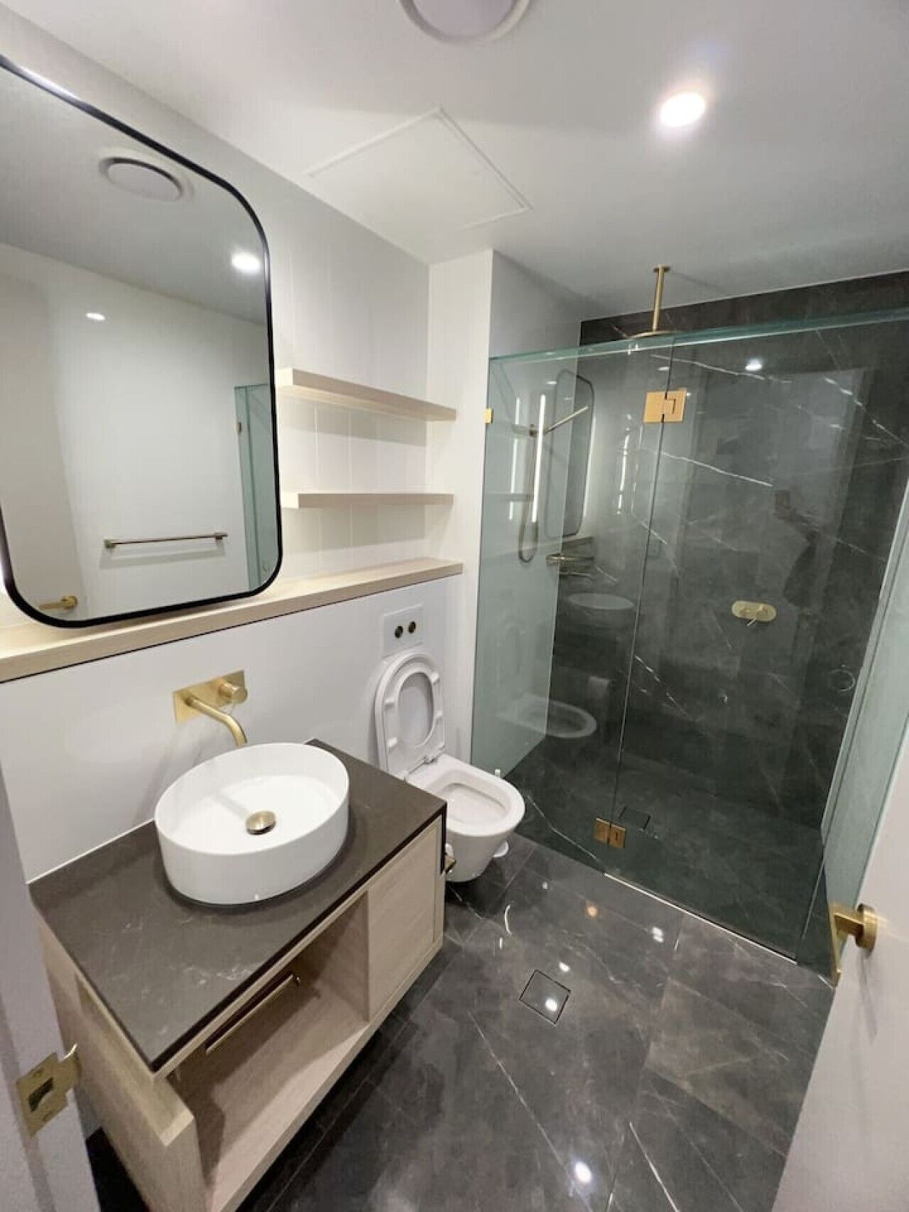 A modern bathroom with a glass-enclosed shower, a white sink, and a toilet.