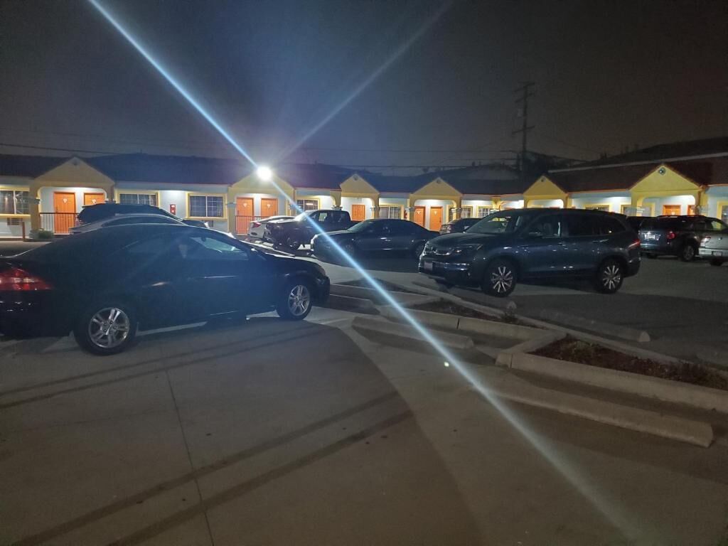 A parking lot with several cars parked in front of a row of yellow buildings with orange doors.