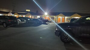 Un estacionamiento con varios coches aparcados frente a un motel con puertas anaranjadas.