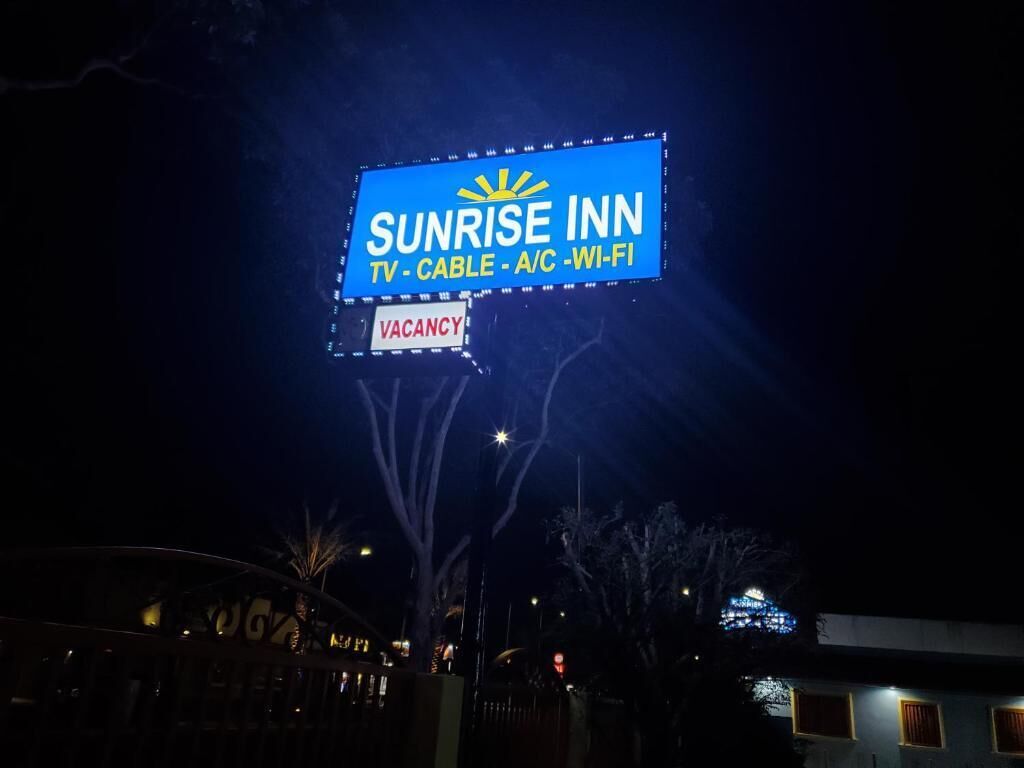 A 'Sunrise Inn' sign with amenities listed as TV, cable, A/C, and Wi-Fi.