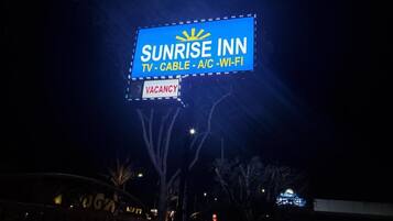 A 'Sunrise Inn' sign with amenities listed as TV, cable, A/C, and Wi-Fi.