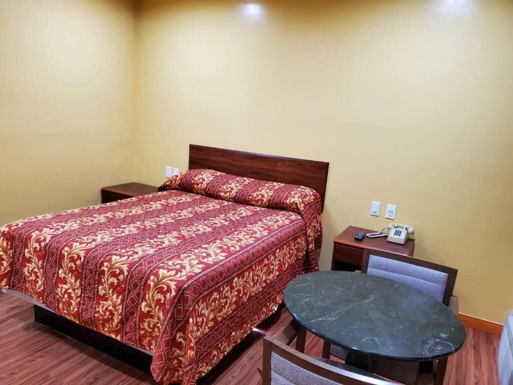 A hotel room with a bed, bedside tables, a round table, and a chair.