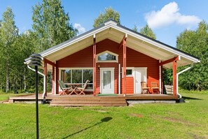 A red wooden cabin with a porch, a door, and a window.