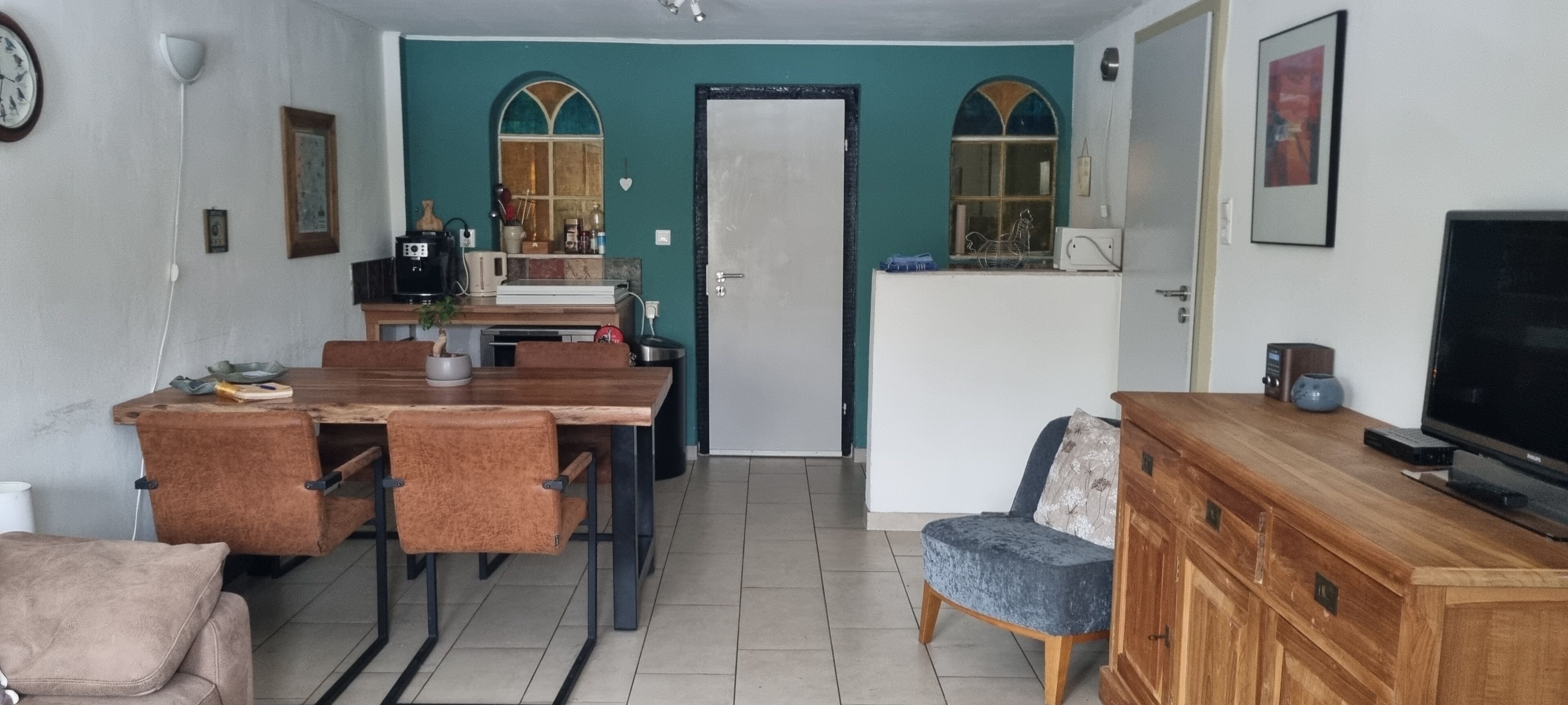 A compact living space with a dining area, a kitchenette, a television, and a seating area.