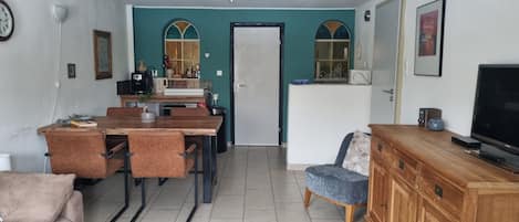 A compact living space with a dining area, a kitchenette, a television, and a seating area.