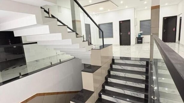 A modern interior with a glass staircase, a flat ceiling, and a minimalist design.