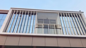 A modern building with a balcony featuring vertical railings and large windows.