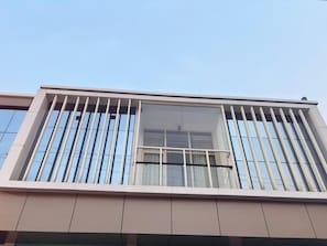 A modern building with a balcony featuring vertical railings and large windows.