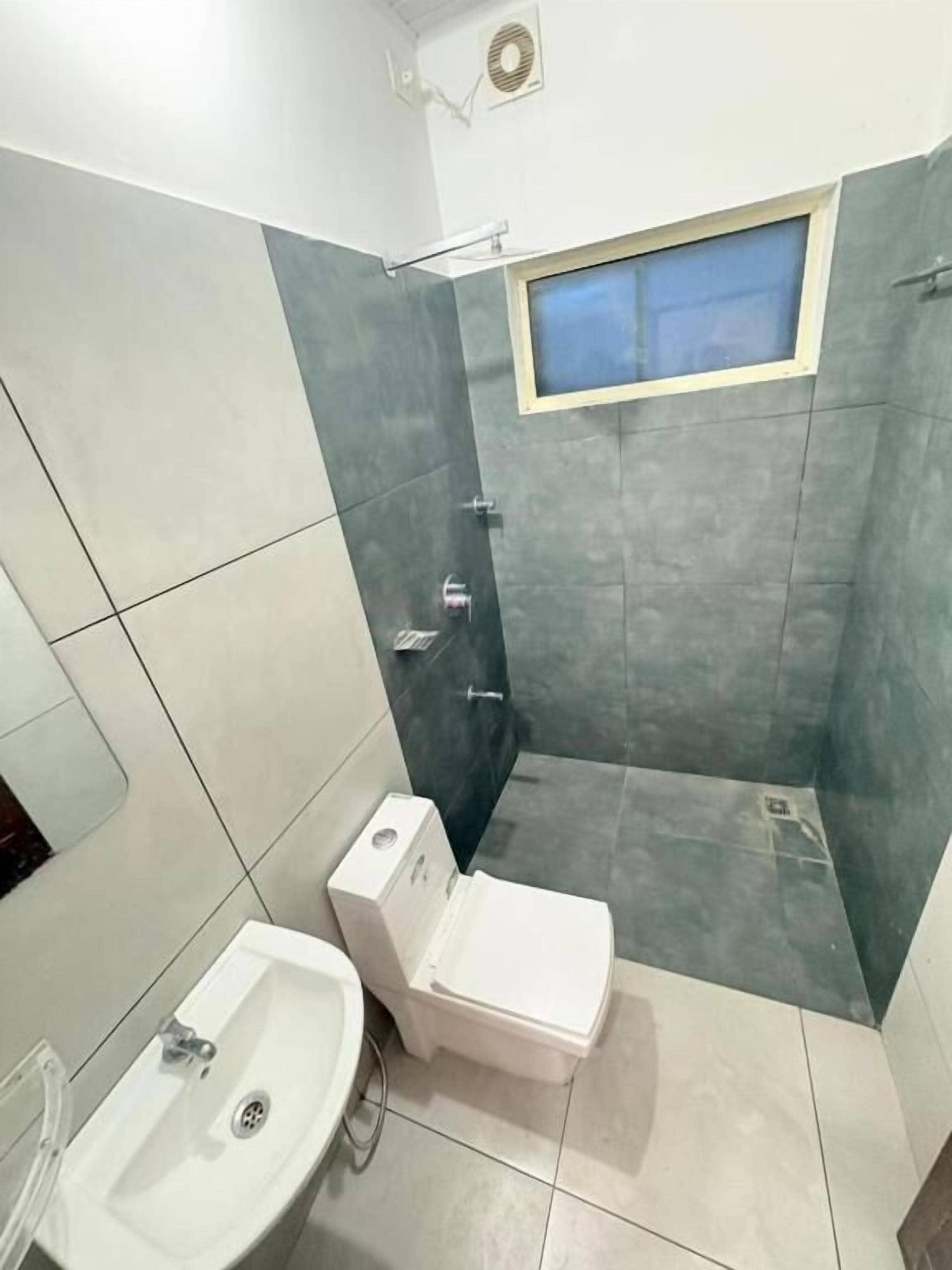 Un baño con inodoro, lavamanos y zona de ducha.