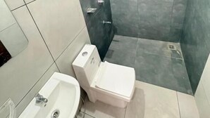 A bathroom with a toilet, sink, and shower area.