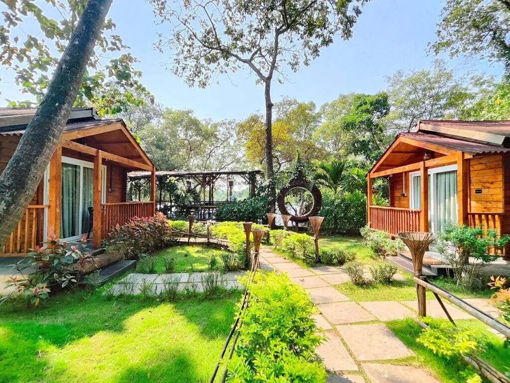 A wooden cabin with a porch, surrounded by a well-maintained garden with a pathway leading to the cabin.