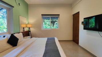 A hotel room with a bed, a window, a television, and a door.