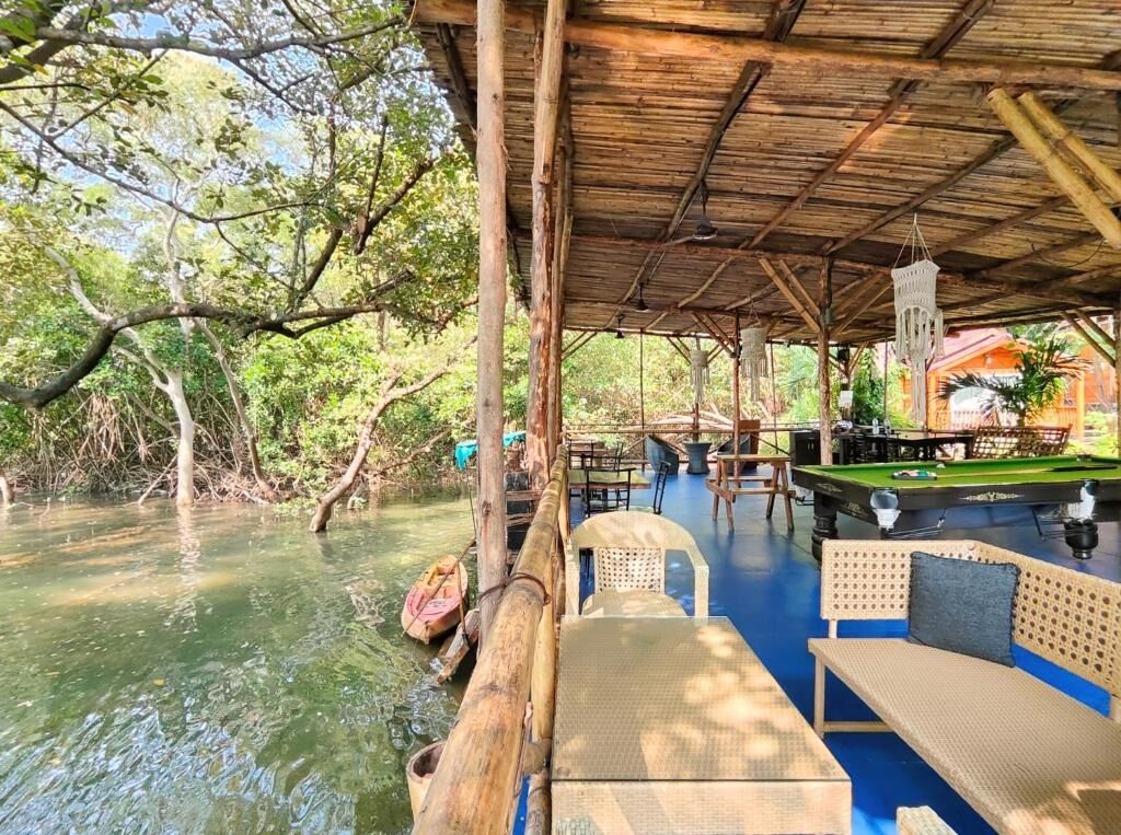 A covered outdoor area with a pool table, seating, and a view of a water body.