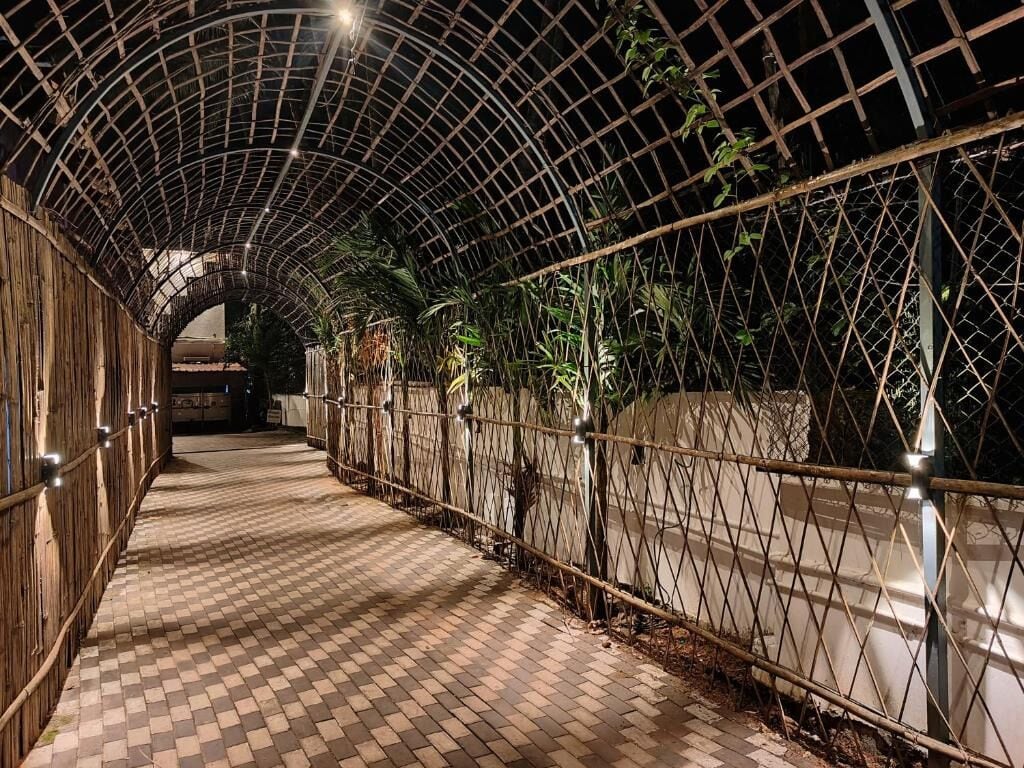 Un pasillo con suelo a cuadros, cerramiento metálico y estructura de techo curva.