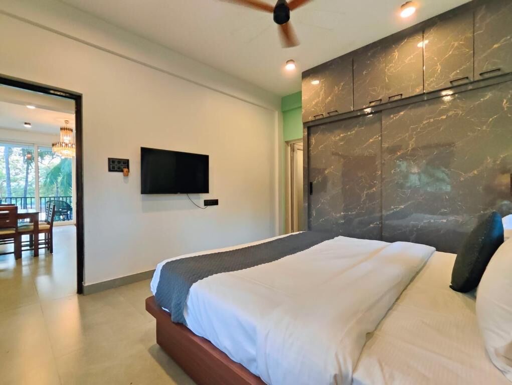 A hotel room with a bed, a ceiling fan, a flat-screen TV, and a marble headboard.