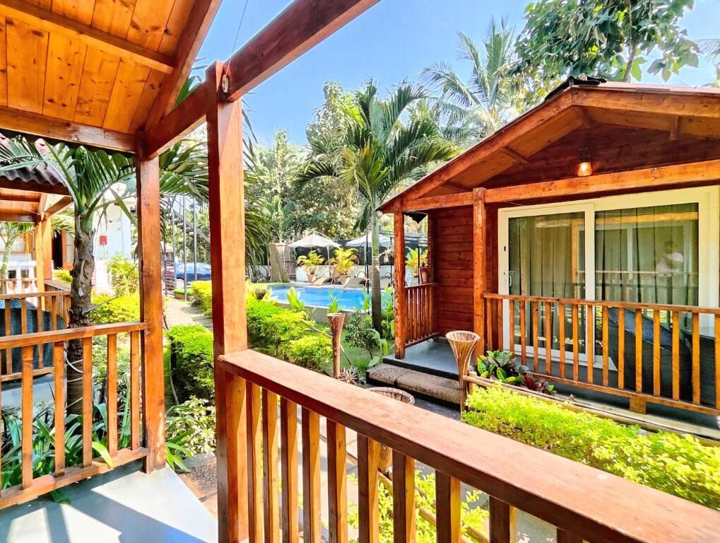 Una terraza de madera con piscina y abundante vegetación.
