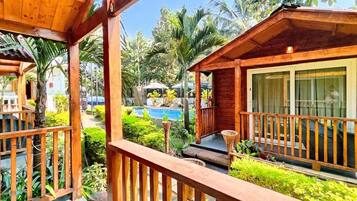 Una terraza de madera con piscina y abundante vegetación.