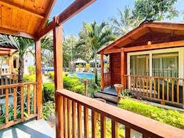 Una terraza de madera con piscina y abundante vegetación.