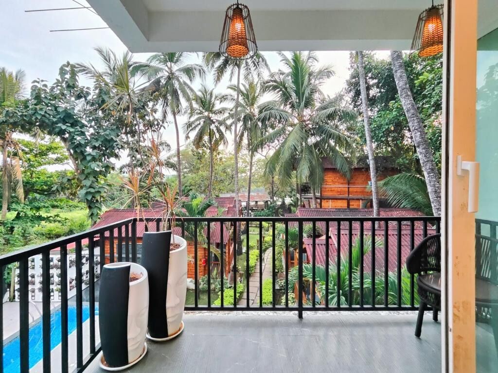 A balcony with a view of a garden and a wooden structure.
