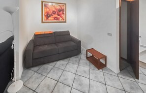 Ein Wohnzimmer mit grauem Sofa, einem kleinen Holztisch und einem Bild an der Wand.
