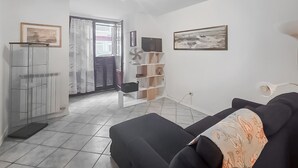 A living room with a sofa, a TV, and a bookshelf. - 2 bedroom gorgeous home in Viareggio (Viareggio)
