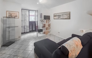Ein Wohnzimmer mit einer Couch, einem Fernseher und einem Bücherregal.