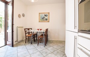 Ein Essbereich mit einem Tisch für zwei Personen, Stühlen, einem Heizkörper und einem Gemälde an der Wand.
