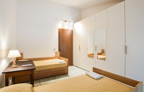 Une chambre d’hôtel comprenant un lit, une table de chevet, une lampe, une armoire et un miroir.