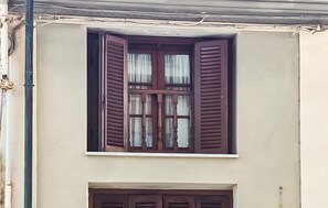 Ein Gebäude mit einem Fenster, das Holzklappläden und einen weißen Fensterbrett hat.