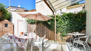 An outdoor patio with a table and chairs, a covered area, and a wall covered in greenery. - 2 bedroom gorgeous home in Viareggio (Viareggio)