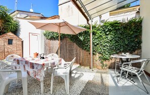 Eine Außenpatio mit Tisch und Stühlen, einem überdachten Bereich und einer mit Grünpflanzen bewachsenen Wand.