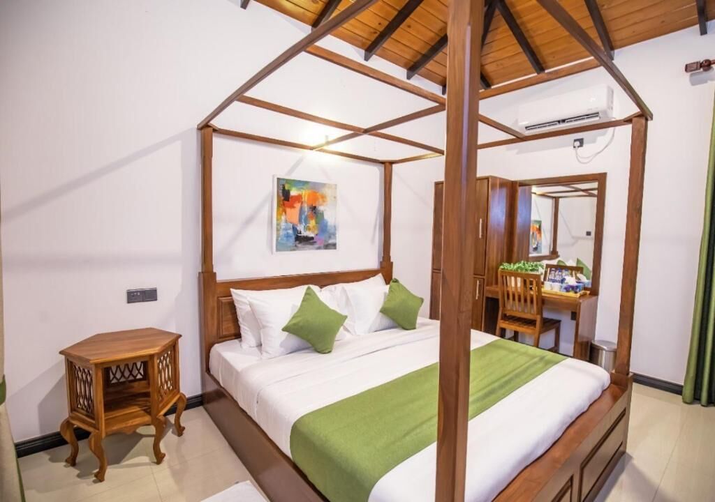 Una cama con dosel de madera, una mesita de noche y una manta verde.