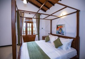 A room with a four-poster bed, a painting on the wall, and a window with curtains.