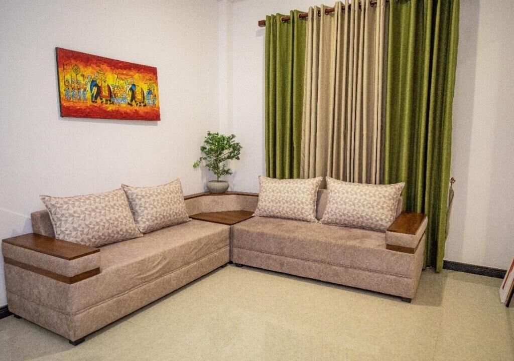 A L-shaped sectional sofa with patterned cushions, a potted plant, and a painting on the wall.