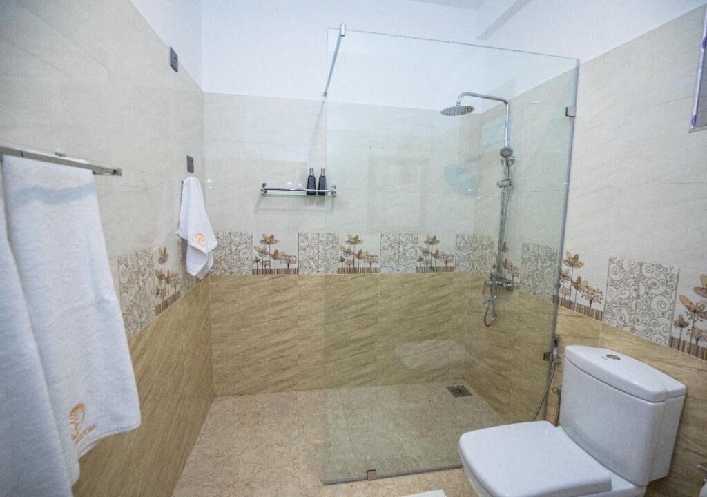 Ein Duschbereich mit Glasabtrennung, eine Toilette und ein Handtuchhalter.