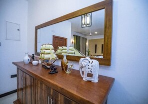 Una encimera de madera con varios objetos, incluyendo un jarrón blanco, un elefante decorativo y una bandeja con elementos amarillos.