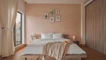A bedroom with a bed, a nightstand, a lamp, and a window with curtains.