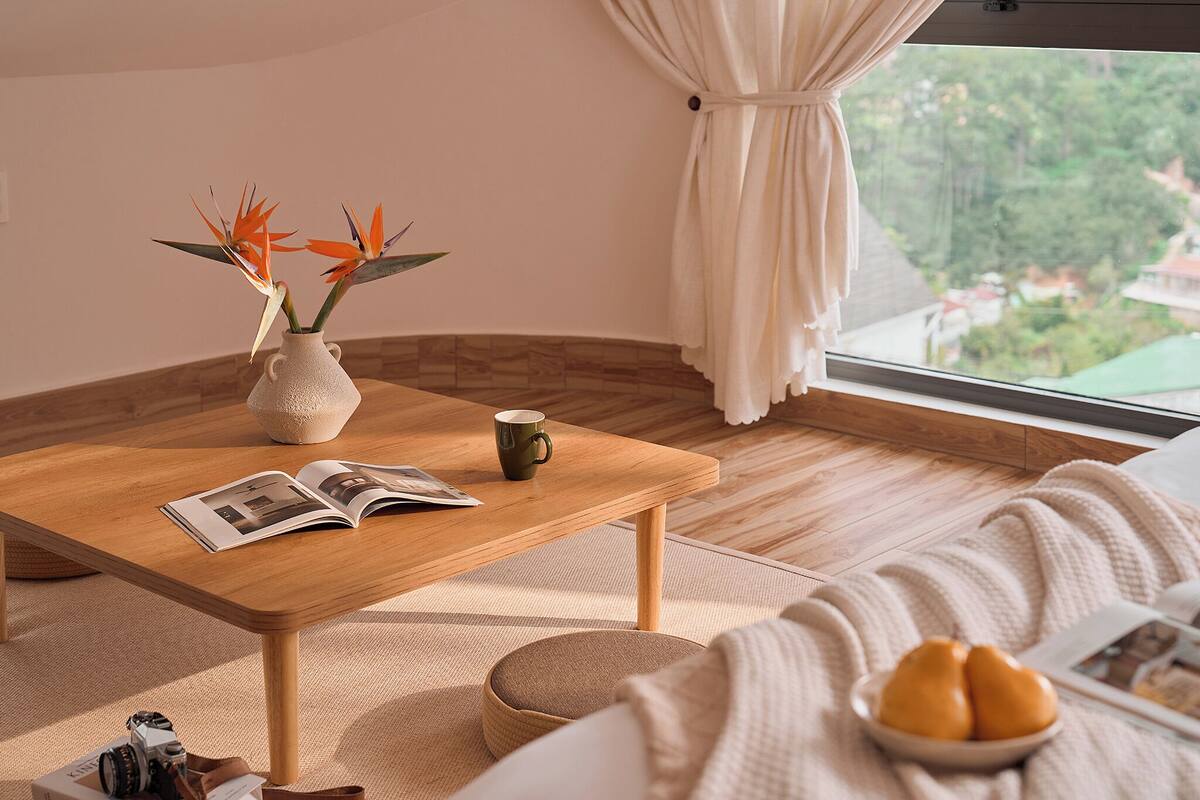 Una sala de estar acogedora con una mesa de centro de madera, un jarrón con flores, una taza y un cuenco de peras.