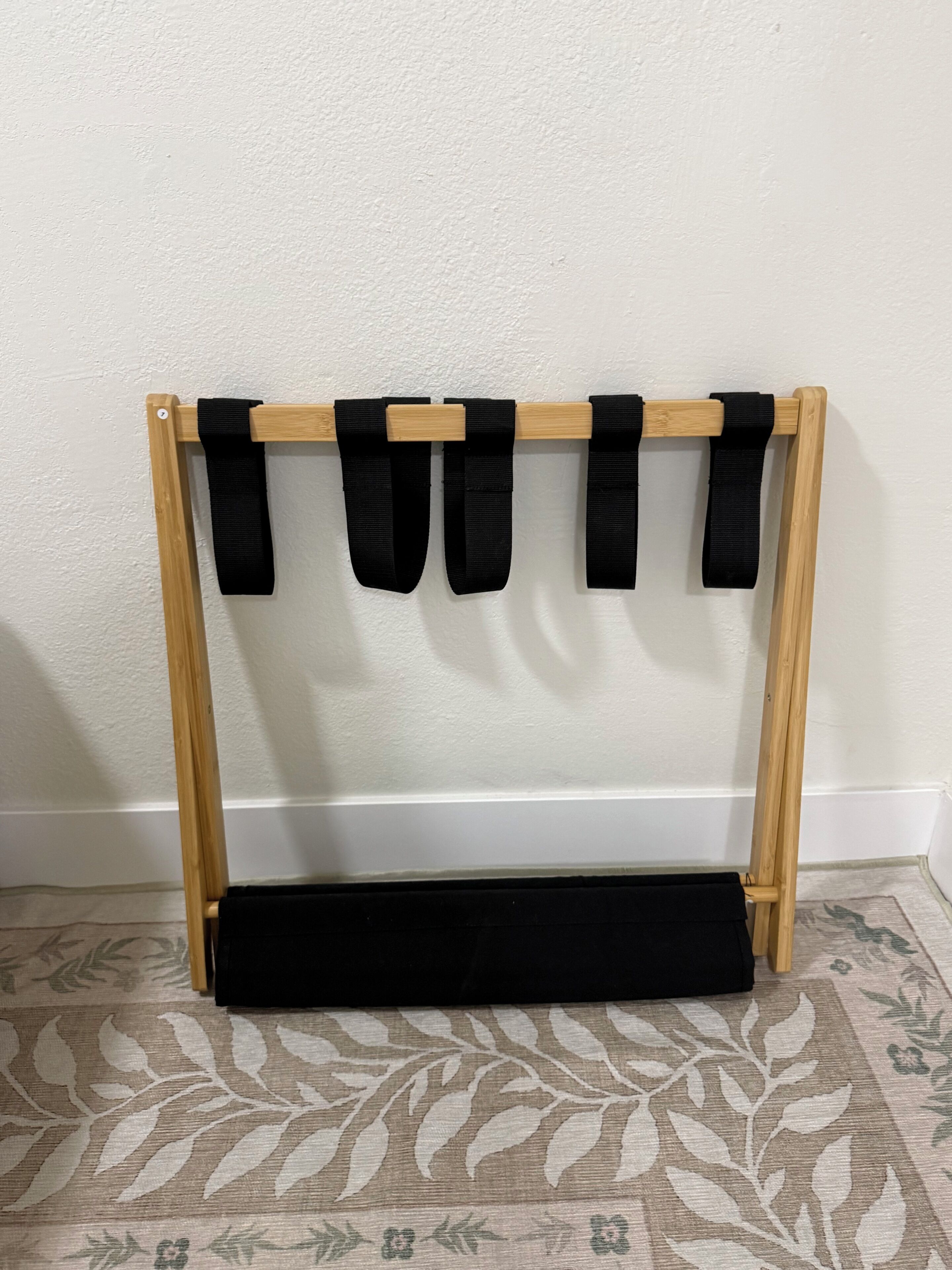 A wooden wall-mounted rack with black straps.