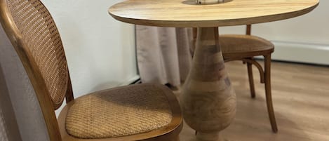 Un coin repas avec une table ronde en bois et deux chaises en osier.